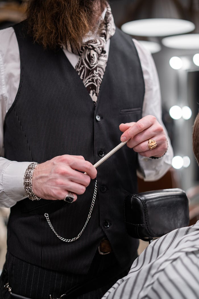 A barber in a stylish vest prepares for a grooming session with a client indoors.